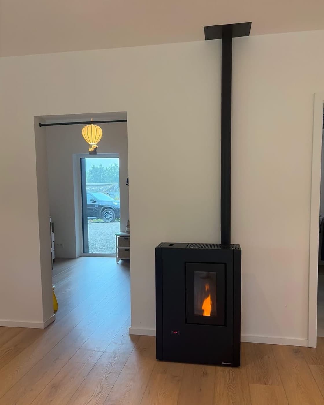 Poêle à granulés noir étroit et rectangulaire, avec écran de commande en façade, conduit vertical